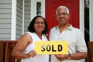 black couple holding a sold sign